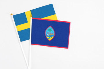 Guam and Sweden stick flags on white background. High quality fabric, miniature national flag. Peaceful global concept.White floor for copy space.