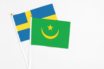 Mauritania and Sweden stick flags on white background. High quality fabric, miniature national flag. Peaceful global concept.White floor for copy space.