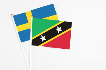 Saint Kitts And Nevis and Sweden stick flags on white background. High quality fabric, miniature national flag. Peaceful global concept.White floor for copy space.