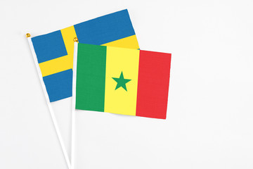 Senegal and Sweden stick flags on white background. High quality fabric, miniature national flag. Peaceful global concept.White floor for copy space.