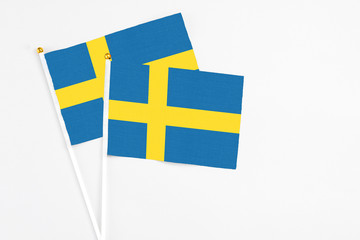 Sweden and Sweden stick flags on white background. High quality fabric, miniature national flag. Peaceful global concept.White floor for copy space.