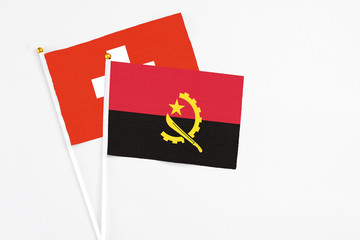 Angola and Switzerland stick flags on white background. High quality fabric, miniature national flag. Peaceful global concept.White floor for copy space.