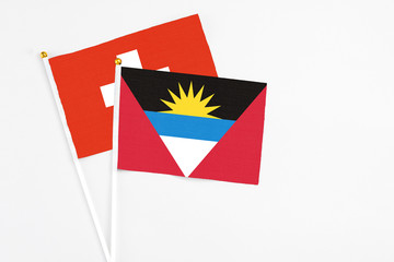 Obraz premium Antigua and Barbuda and Switzerland stick flags on white background. High quality fabric, miniature national flag. Peaceful global concept.White floor for copy space.