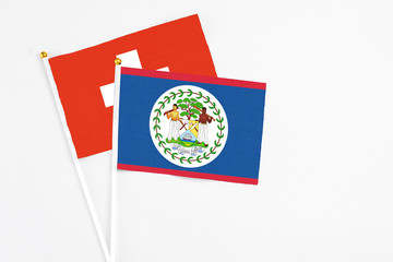 Belize and Switzerland stick flags on white background. High quality fabric, miniature national flag. Peaceful global concept.White floor for copy space.