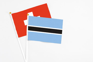 Botswana and Switzerland stick flags on white background. High quality fabric, miniature national flag. Peaceful global concept.White floor for copy space.