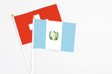 Guatemala and Switzerland stick flags on white background. High quality fabric, miniature national flag. Peaceful global concept.White floor for copy space.