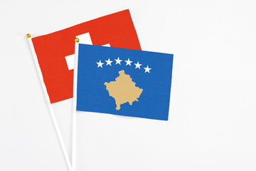 Kosovo and Switzerland stick flags on white background. High quality fabric, miniature national flag. Peaceful global concept.White floor for copy space.