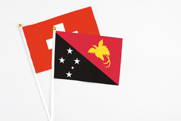 Papua New Guinea and Switzerland stick flags on white background. High quality fabric, miniature national flag. Peaceful global concept.White floor for copy space.