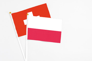 Poland and Switzerland stick flags on white background. High quality fabric, miniature national flag. Peaceful global concept.White floor for copy space.