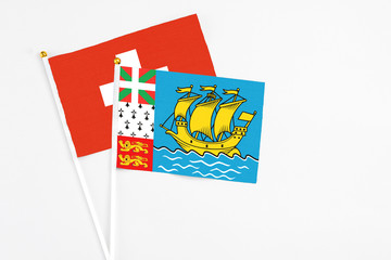 Saint Pierre And Miquelon and Switzerland stick flags on white background. High quality fabric, miniature national flag. Peaceful global concept.White floor for copy space.