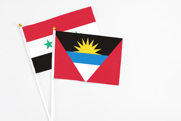 Antigua and Barbuda and Syria stick flags on white background. High quality fabric, miniature national flag. Peaceful global concept.White floor for copy space.