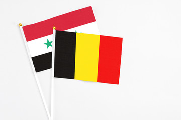 Belgium and Syria stick flags on white background. High quality fabric, miniature national flag. Peaceful global concept.White floor for copy space.