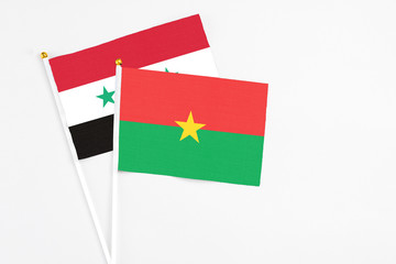 Burkina Faso and Syria stick flags on white background. High quality fabric, miniature national flag. Peaceful global concept.White floor for copy space.