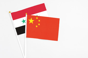 China and Syria stick flags on white background. High quality fabric, miniature national flag. Peaceful global concept.White floor for copy space.