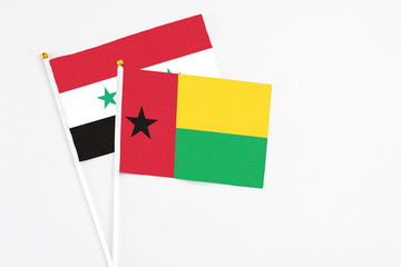 Guinea Bissau and Syria stick flags on white background. High quality fabric, miniature national...