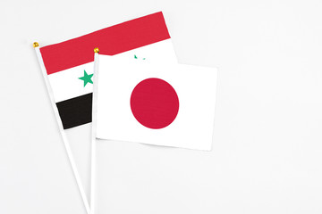 Japan and Syria stick flags on white background. High quality fabric, miniature national flag....