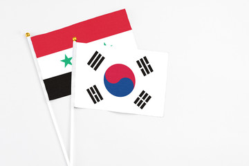 South Korea and Syria stick flags on white background. High quality fabric, miniature national flag. Peaceful global concept.White floor for copy space.