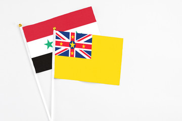 Niue and Syria stick flags on white background. High quality fabric, miniature national flag....