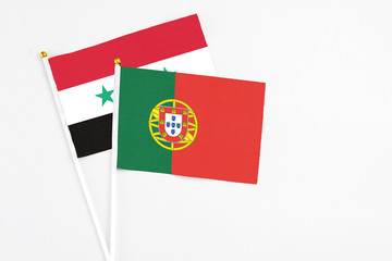 Portugal and Syria stick flags on white background. High quality fabric, miniature national flag. Peaceful global concept.White floor for copy space.
