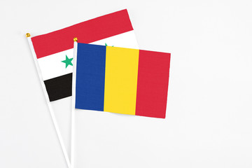 Romania and Syria stick flags on white background. High quality fabric, miniature national flag. Peaceful global concept.White floor for copy space.