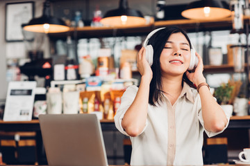 Lifestyle freelance woman he using earphones listening music during working on laptop computer