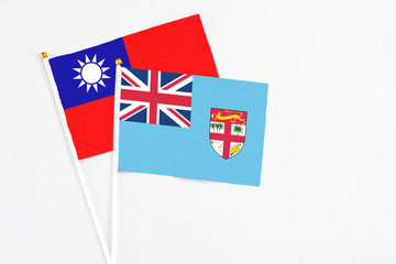 Fototapeta premium Fiji and Taiwan stick flags on white background. High quality fabric, miniature national flag. Peaceful global concept.White floor for copy space.