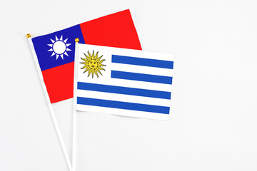 Uruguay and Taiwan stick flags on white background. High quality fabric, miniature national flag. Peaceful global concept.White floor for copy space.