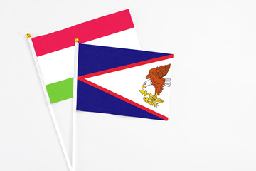 American Samoa and Tajikistan stick flags on white background. High quality fabric, miniature national flag. Peaceful global concept.White floor for copy space.