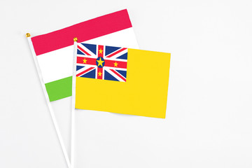 Niue and Tajikistan stick flags on white background. High quality fabric, miniature national flag. Peaceful global concept.White floor for copy space.