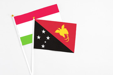 Papua New Guinea and Tajikistan stick flags on white background. High quality fabric, miniature national flag. Peaceful global concept.White floor for copy space.