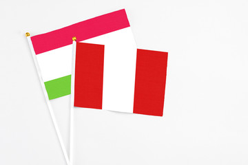 Fototapeta premium Peru and Tajikistan stick flags on white background. High quality fabric, miniature national flag. Peaceful global concept.White floor for copy space.