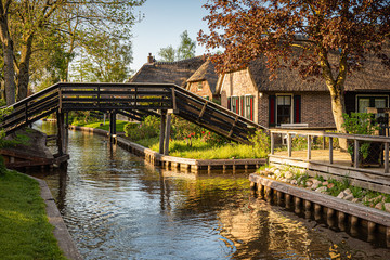 Fototapeta na wymiar Lovely landscape along canal with footbridges and picturesque houses, Giethoorn, Netherlands