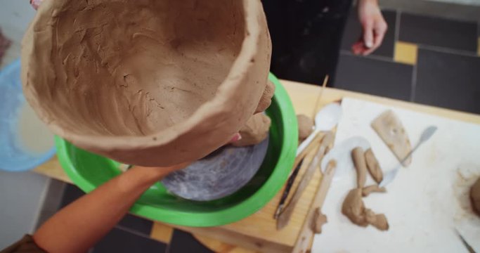Closeup of young female hands creating clay form on pottery table. Handmade art objects shopping online. Successful freelance business lifestyle. Creative classroom modern training for kids educating