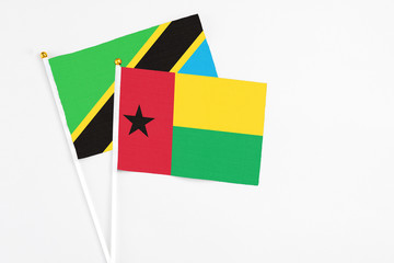 Guinea Bissau and Tanzania stick flags on white background. High quality fabric, miniature national flag. Peaceful global concept.White floor for copy space.