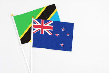 Fototapeta premium New Zealand and Tanzania stick flags on white background. High quality fabric, miniature national flag. Peaceful global concept.White floor for copy space.