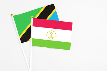 Tajikistan and Tanzania stick flags on white background. High quality fabric, miniature national flag. Peaceful global concept.White floor for copy space.
