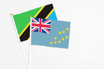 Fototapeta premium Tuvalu and Tanzania stick flags on white background. High quality fabric, miniature national flag. Peaceful global concept.White floor for copy space.