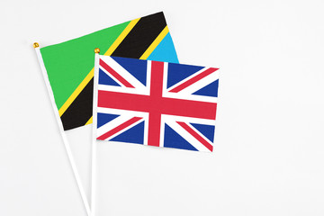 Fototapeta premium United Kingdom and Tanzania stick flags on white background. High quality fabric, miniature national flag. Peaceful global concept.White floor for copy space.