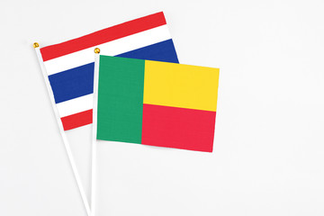 Fototapeta premium Benin and Thailand stick flags on white background. High quality fabric, miniature national flag. Peaceful global concept.White floor for copy space.