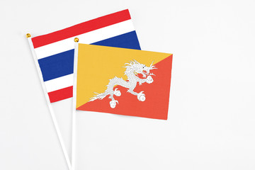 Bhutan and Thailand stick flags on white background. High quality fabric, miniature national flag. Peaceful global concept.White floor for copy space.