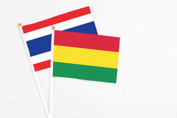 Bolivia and Thailand stick flags on white background. High quality fabric, miniature national flag. Peaceful global concept.White floor for copy space.