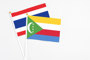 Comoros and Thailand stick flags on white background. High quality fabric, miniature national flag. Peaceful global concept.White floor for copy space.