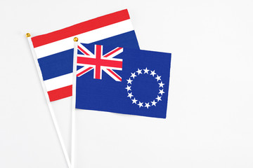 Fototapeta premium Cook Islands and Thailand stick flags on white background. High quality fabric, miniature national flag. Peaceful global concept.White floor for copy space.