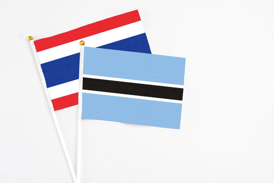 Botswana and Thailand stick flags on white background. High quality fabric, miniature national flag. Peaceful global concept.White floor for copy space.