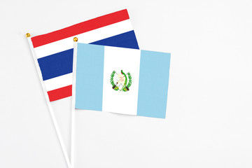Guatemala and Thailand stick flags on white background. High quality fabric, miniature national flag. Peaceful global concept.White floor for copy space.