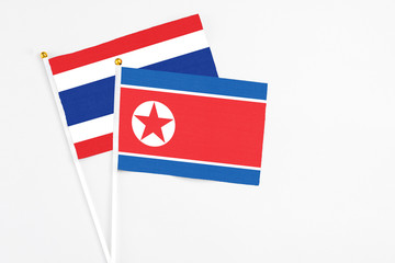 North Korea and Thailand stick flags on white background. High quality fabric, miniature national flag. Peaceful global concept.White floor for copy space.