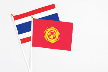 Kyrgyzstan and Thailand stick flags on white background. High quality fabric, miniature national flag. Peaceful global concept.White floor for copy space.