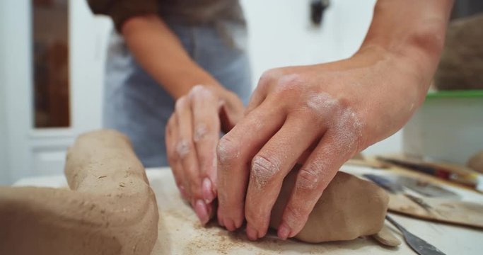 Female hands creates forms shape jug white clay close-up macro. Sculpts clay pot. Modeling clay. Caucasian woman making vessel of white-clay on pottery table. Ukraine cultural traditions.