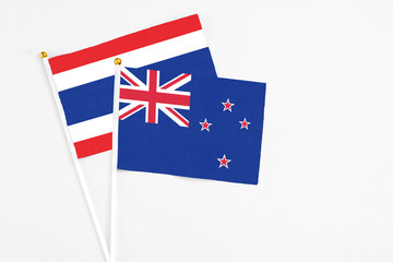 Fototapeta premium New Zealand and Thailand stick flags on white background. High quality fabric, miniature national flag. Peaceful global concept.White floor for copy space.