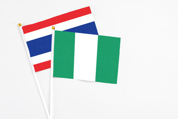 Nigeria and Thailand stick flags on white background. High quality fabric, miniature national flag. Peaceful global concept.White floor for copy space.